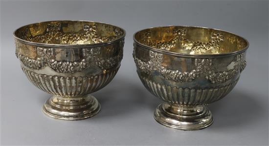 A near pair of silver pedestal rose bowls, half-fluted and embossed with ribbon-tied swags